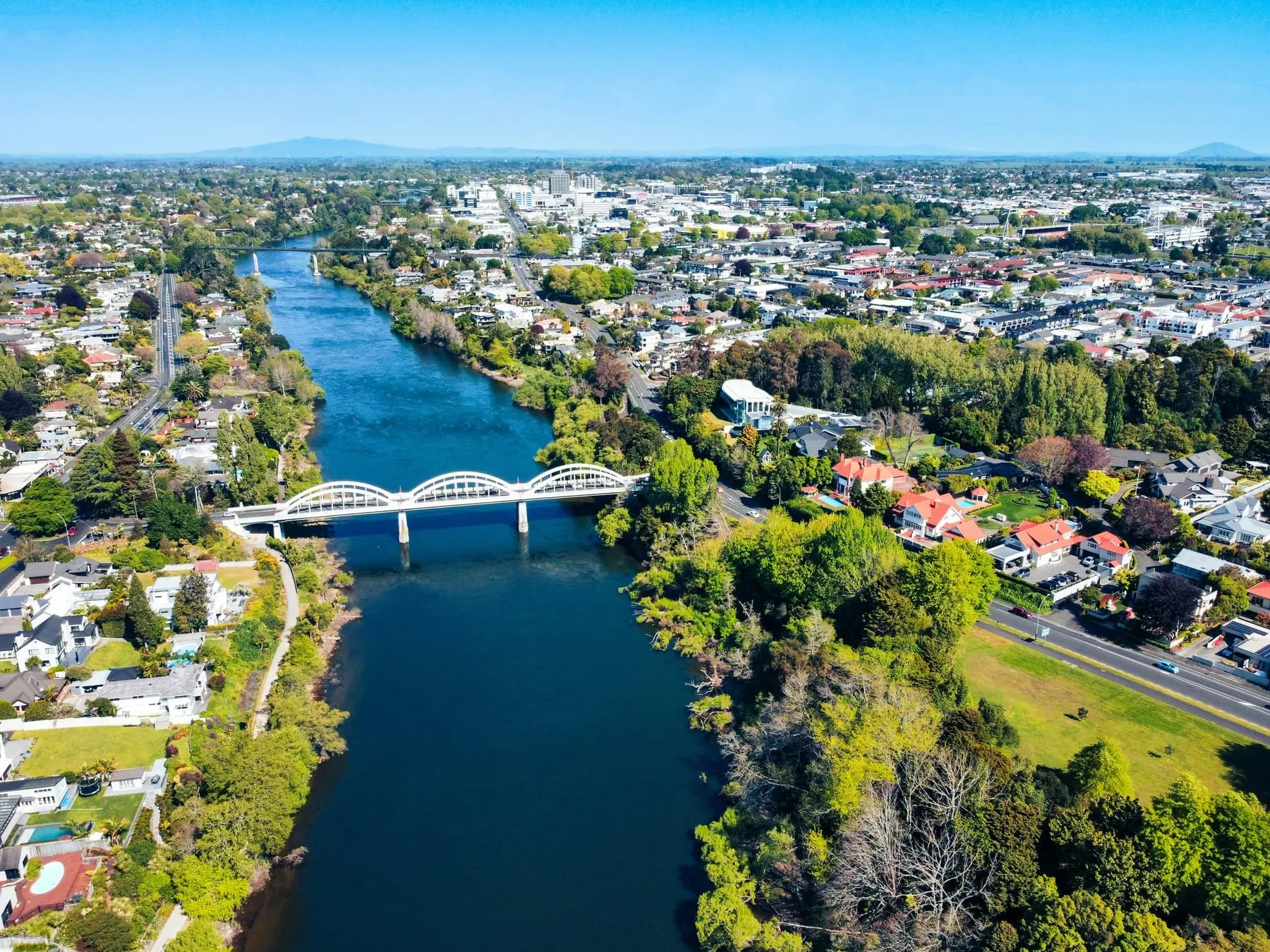 Aerial view of Hamilton, New Zealand, showing the Waikato River curving through the city past an arched road bridge