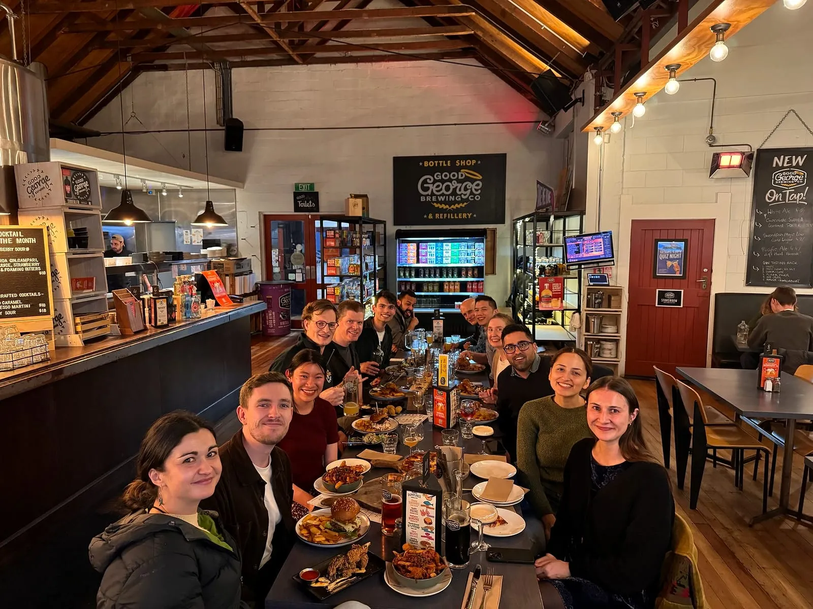 The Waikato Hospital plastic surgery team at a long dinner table inside Good George Brewing Co. in Hamilton, sharing burgers and beers